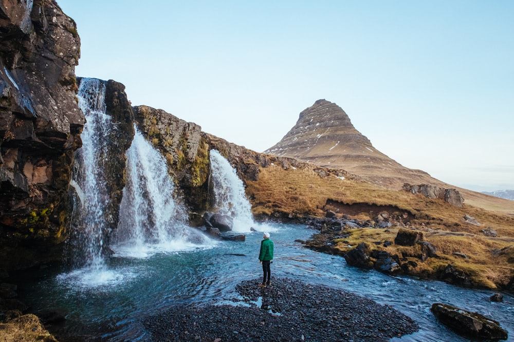 man standing near waterfalls