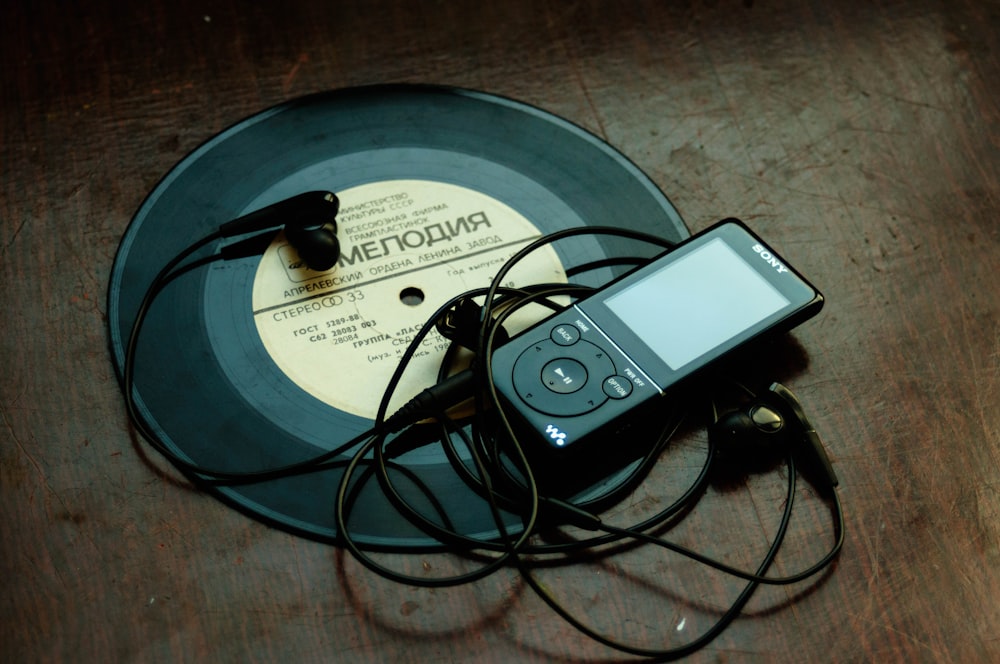 in-ear headphones plugged in black Sony Walkman on vinyl record