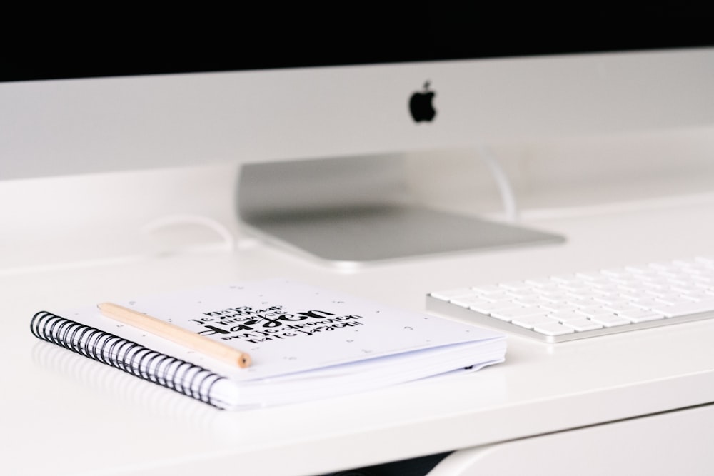 white book beside iMac and keyboard on table