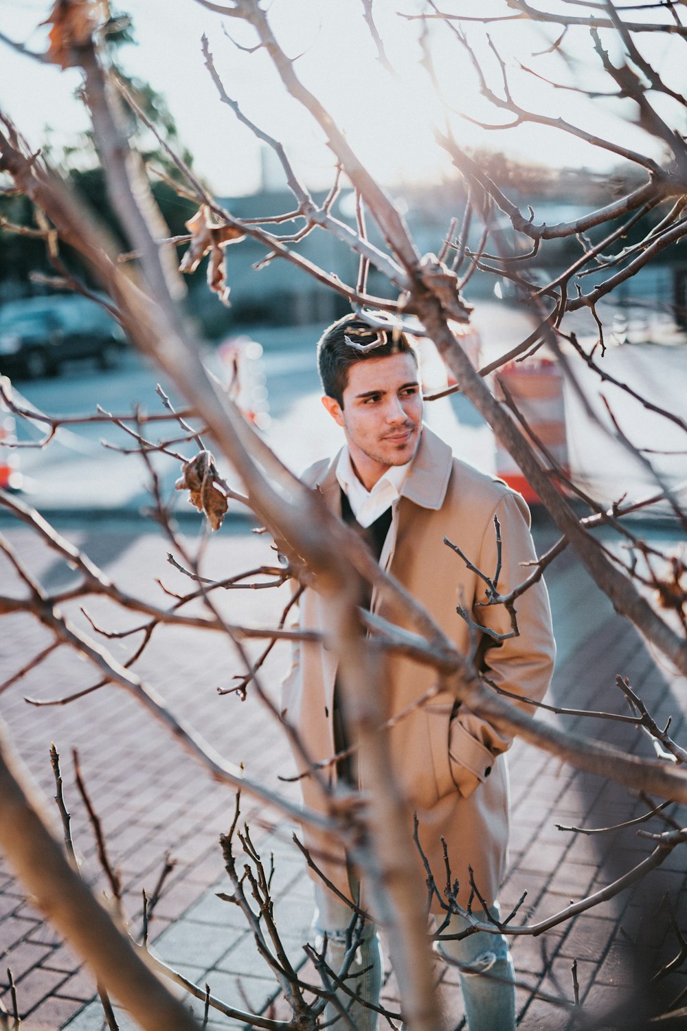 갈색 코트를 입은 남자가 나무 근처에 서 있다
