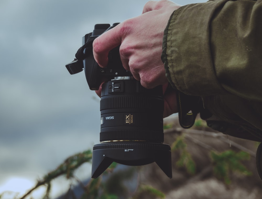 persona sosteniendo una cámara DSLR negra