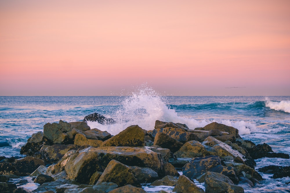 rocks surrounded by ocean during sunset