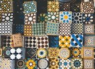 Close-up of handcrafted Moroccan tiles blending black, beige, and gold hues in intricate patterns.