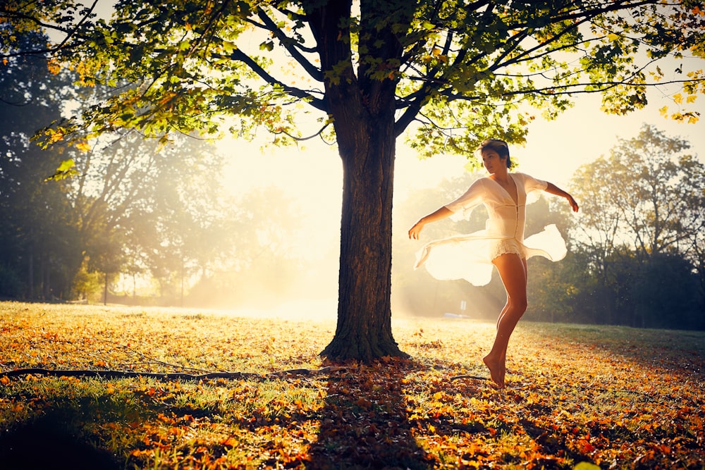 woman spreading arms beside tree during daytime