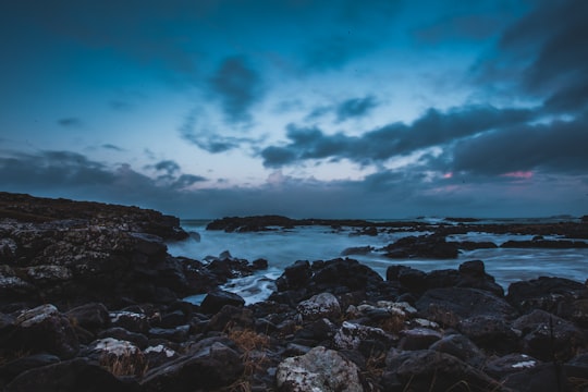 black rock formation near sea under gloomy sky in Dunseverick United Kingdom