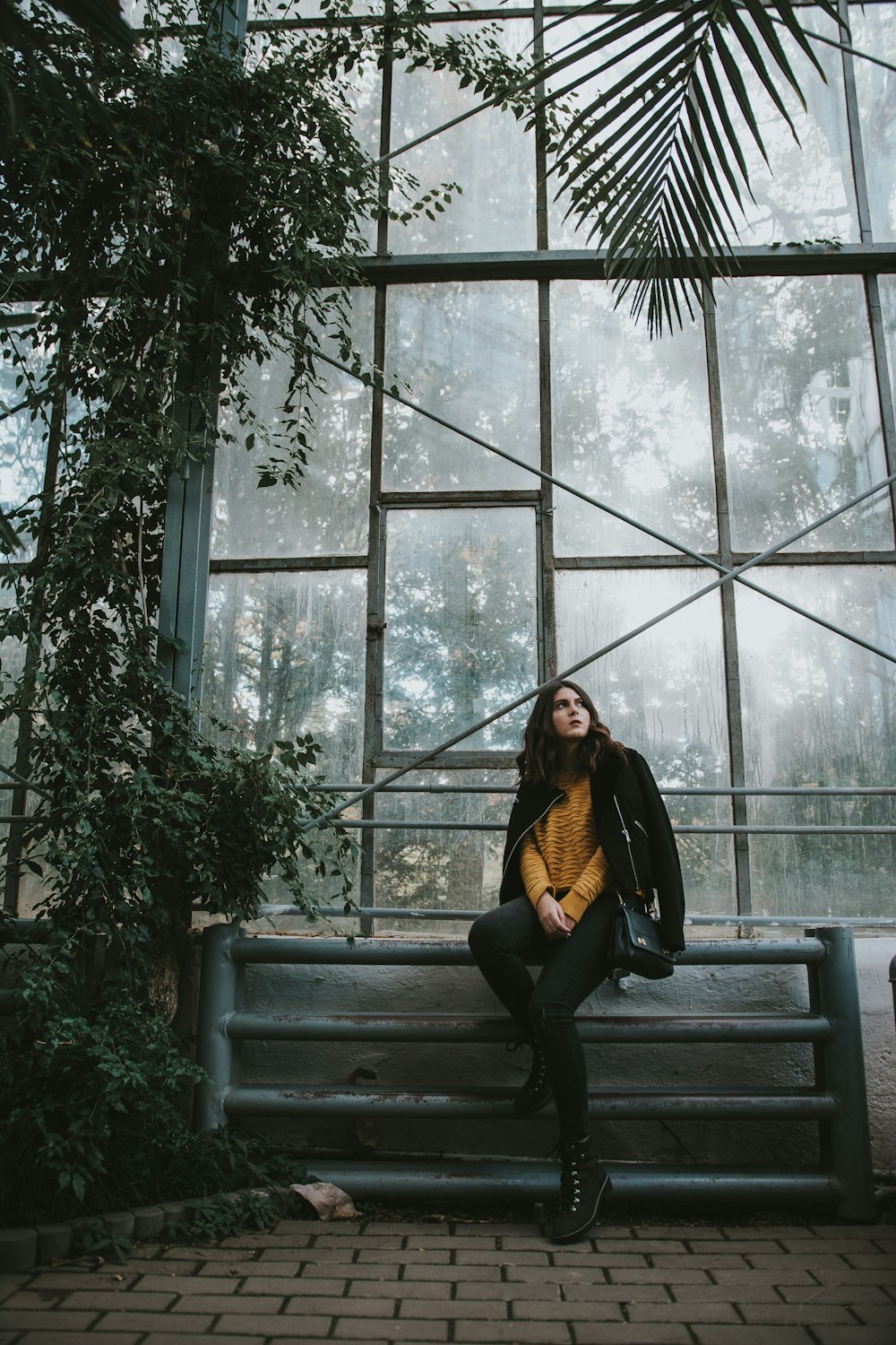 woman sitting on gray metal bar near glass wall