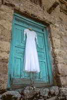 A vibrant dress hanging on a rustic wooden door with sunlight filtering through.