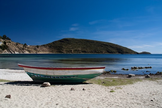 white and green boat near body of water in Isla del Sol Bolivia