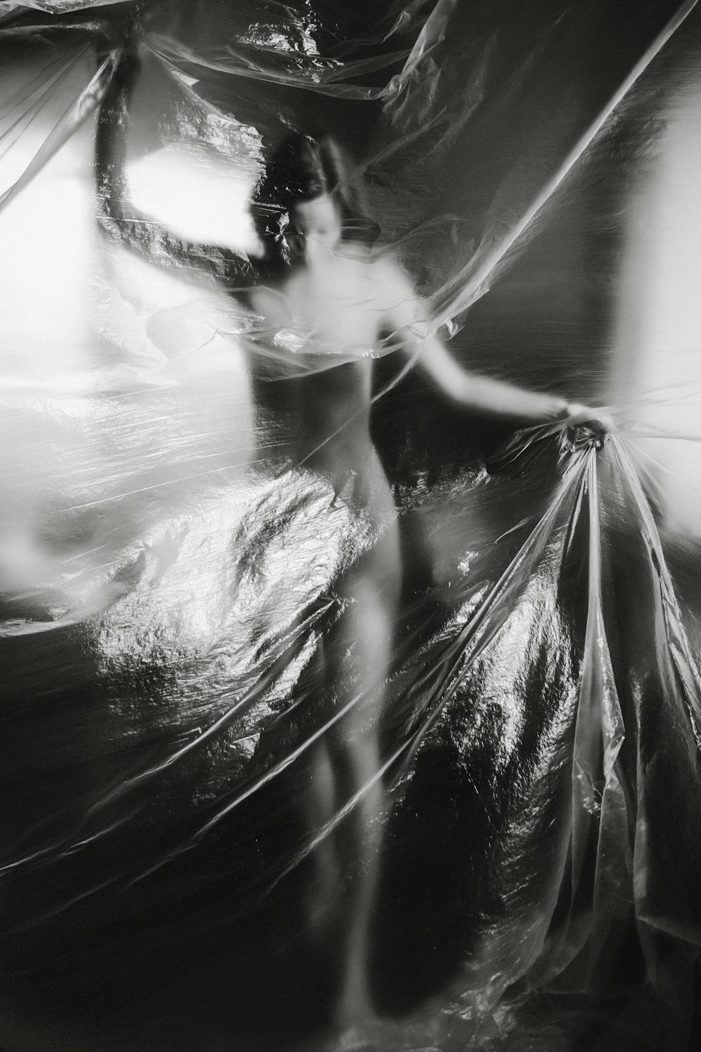 a black and white photo of a woman wrapped in plastic