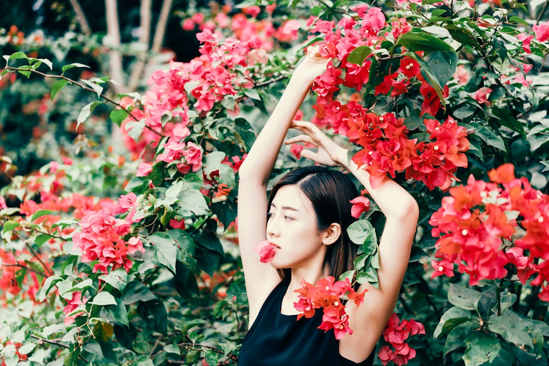 woman standing in front of red flowers