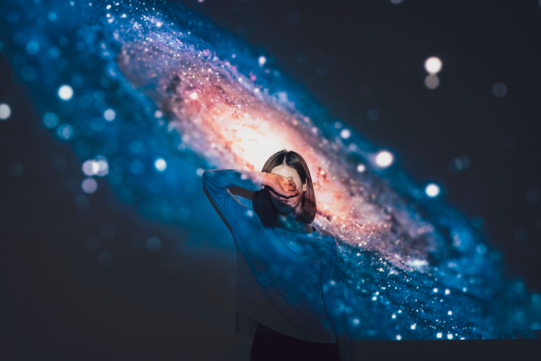 woman covering her face using right hand with galaxy background