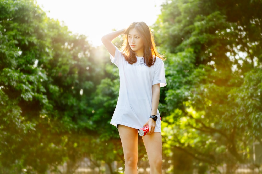 selective focus photo of woman standing behind green trees