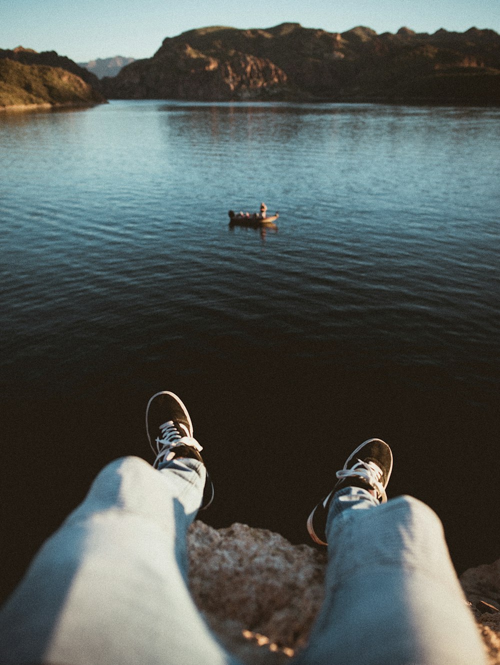 Persona sentada en una roca cerca de un cuerpo de agua