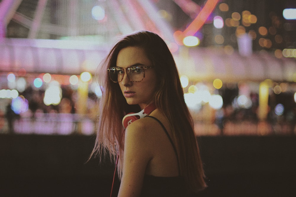 Eine Frau mit Brille, die vor einem Riesenrad steht