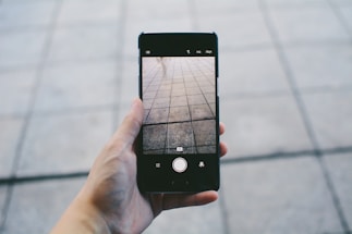 Close-up of a craftsman’s hands holding a tile and a phone, ready to assist customers