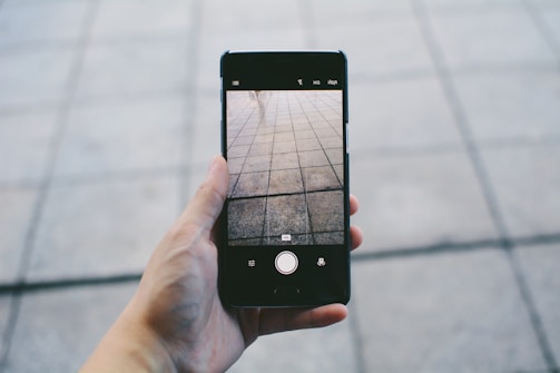 Close-up of a craftsman’s hands holding a tile and a phone, ready to assist customers