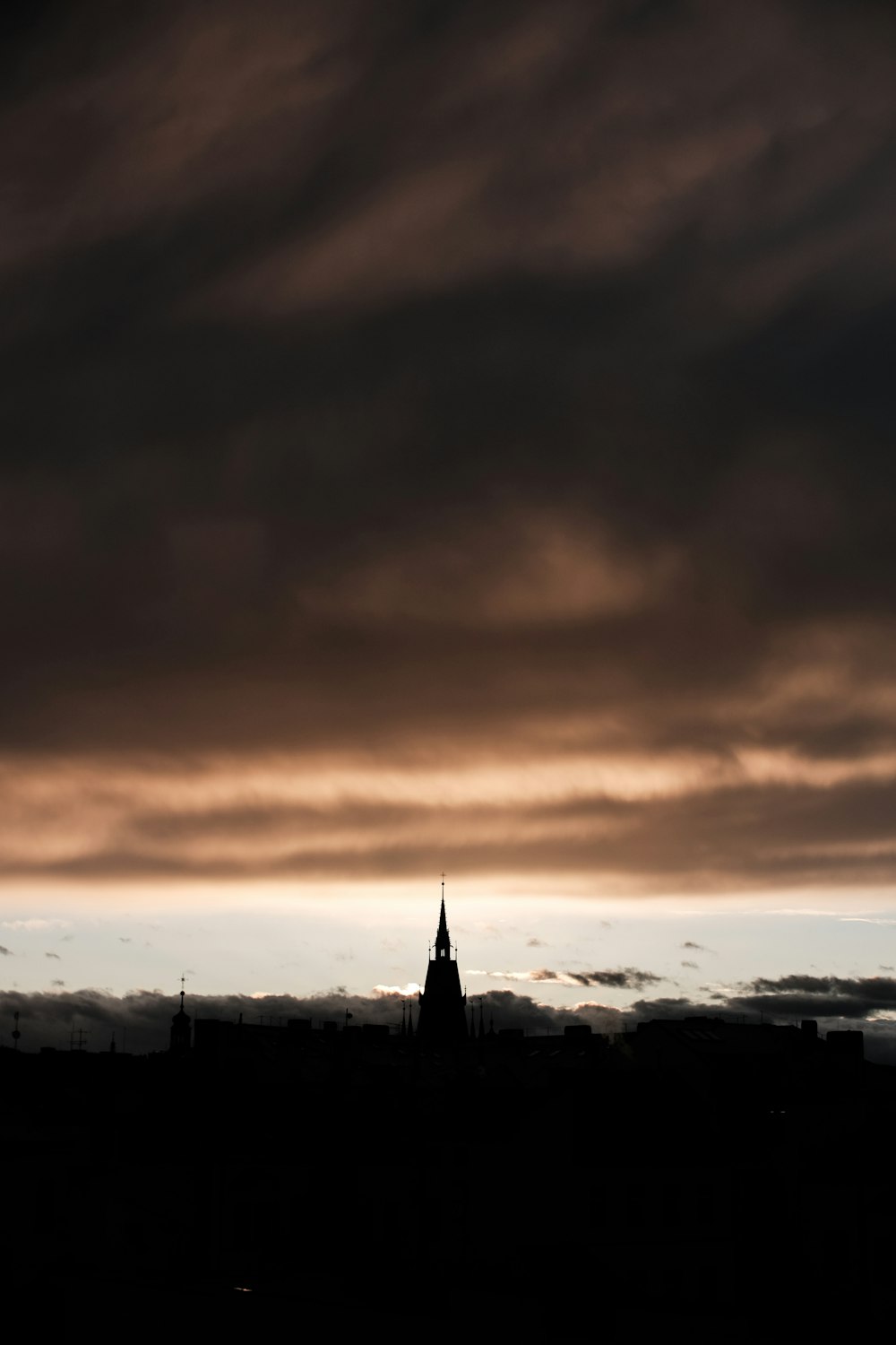 silhouette of tower under gray clouds during daytime