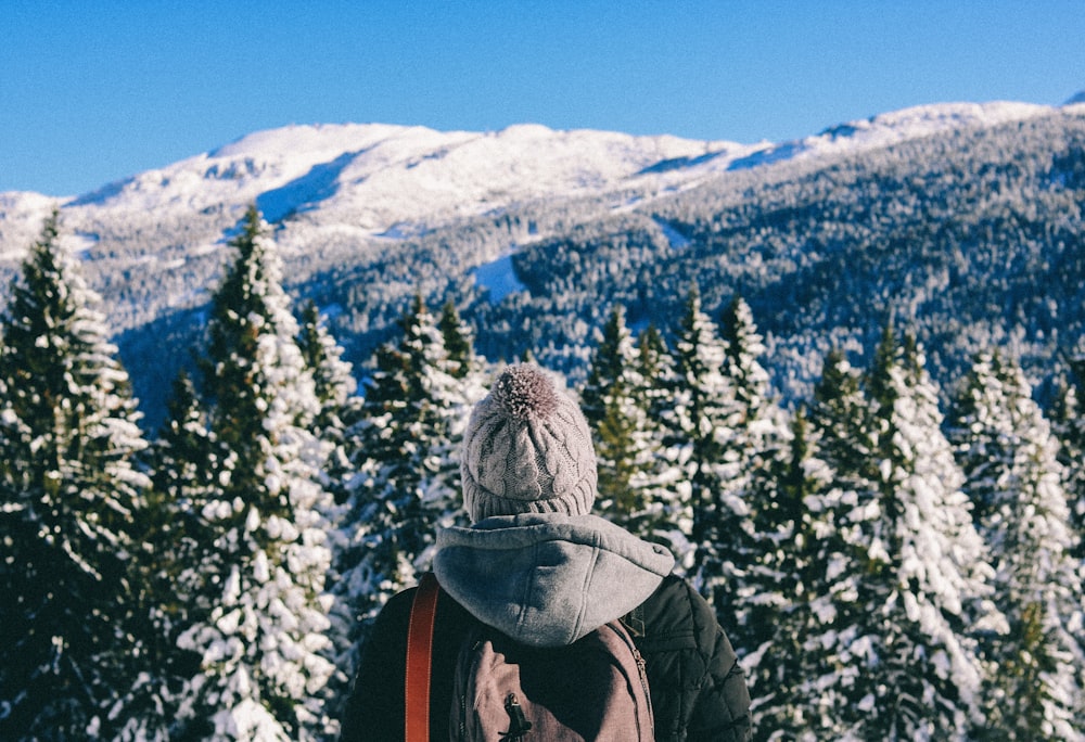 person standing in front of trees covered by snow