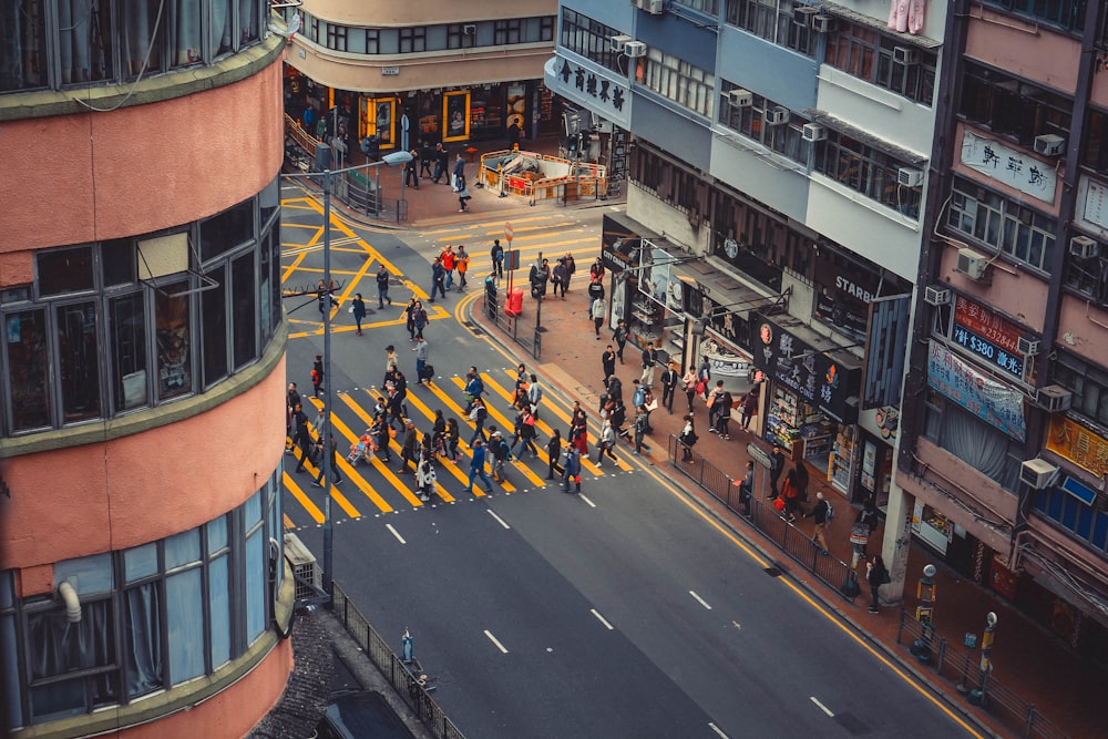 a group of people walking across a street next to tall buildings