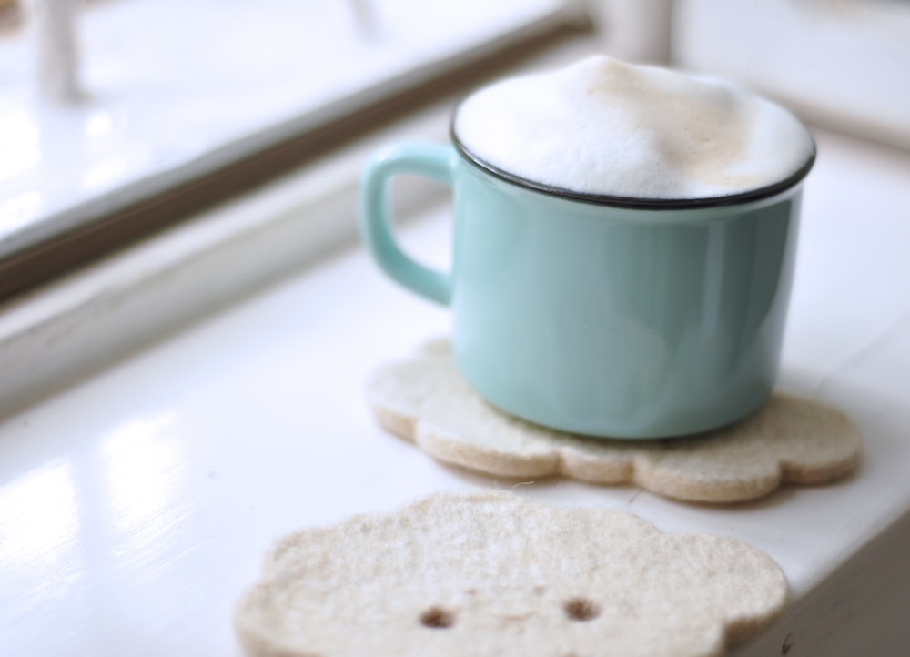 teal ceramic mug with creams near window