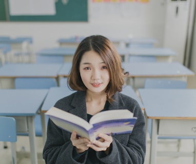 woman reading book sitting on chair in room