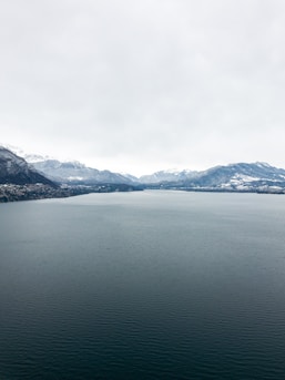 An expansive view of icy mountains reflecting calm waters.