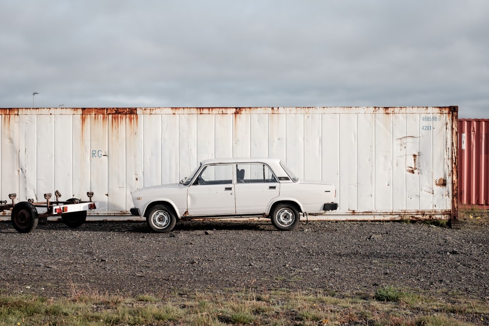 white sedan parked near white shipping container