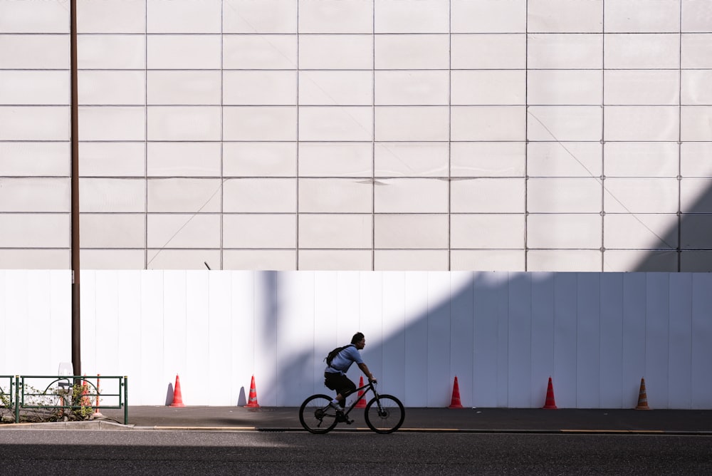 Mann fährt tagsüber Fahrrad in der Nähe der weißen Wand