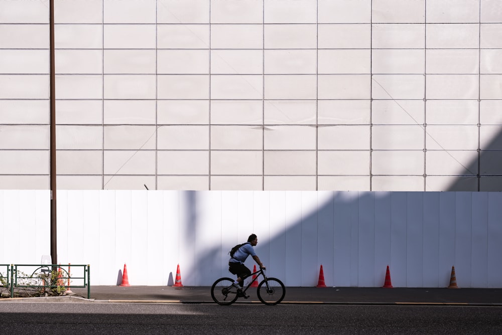 Hombre montando en bicicleta cerca de la pared blanca durante el día