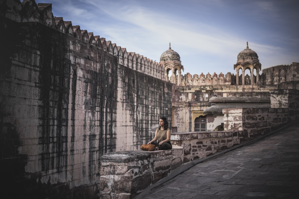 woman sitting on concrete rail during daytime