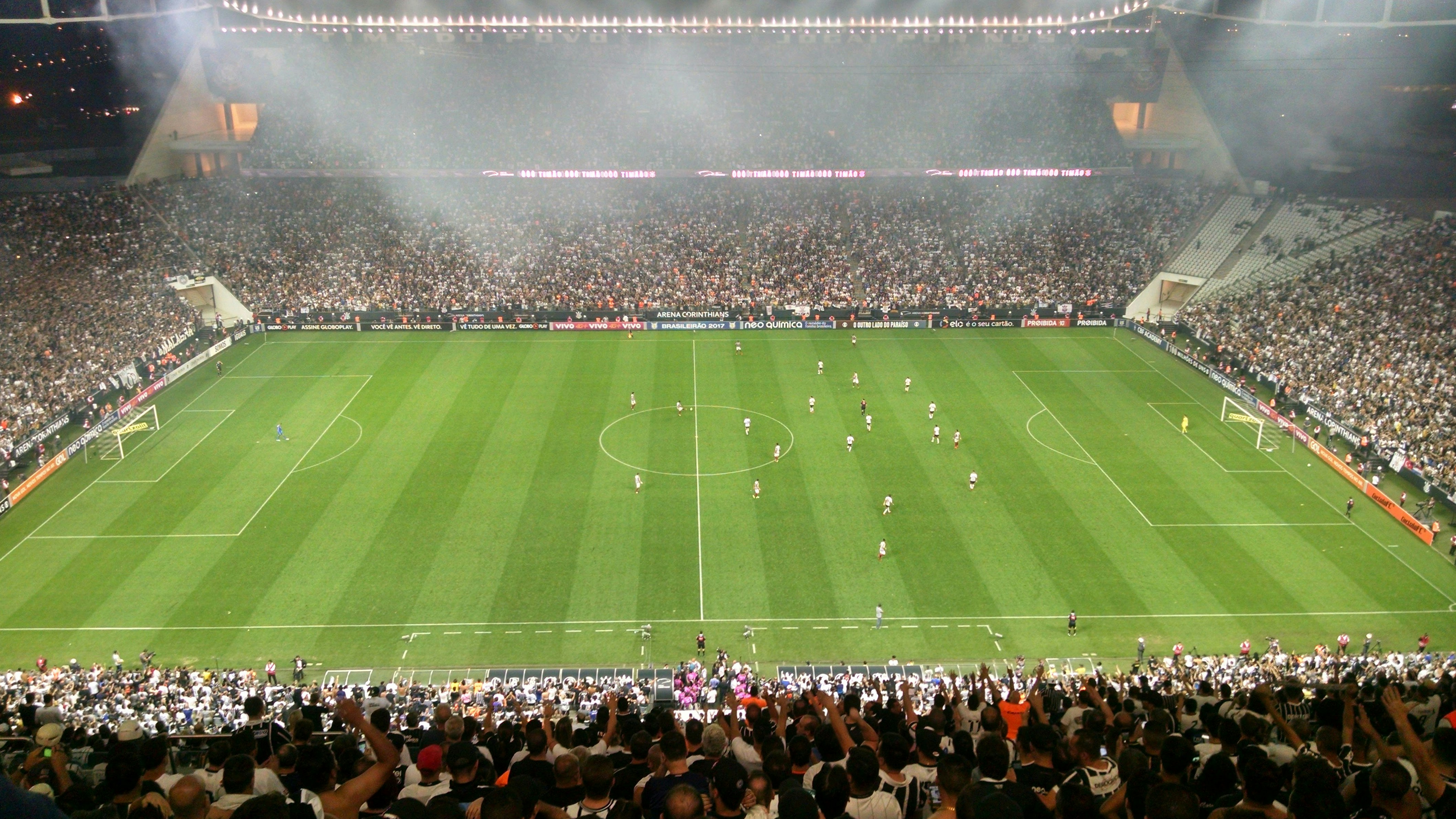 Soccer players in intense formation on illuminated field with crowd cheering in background