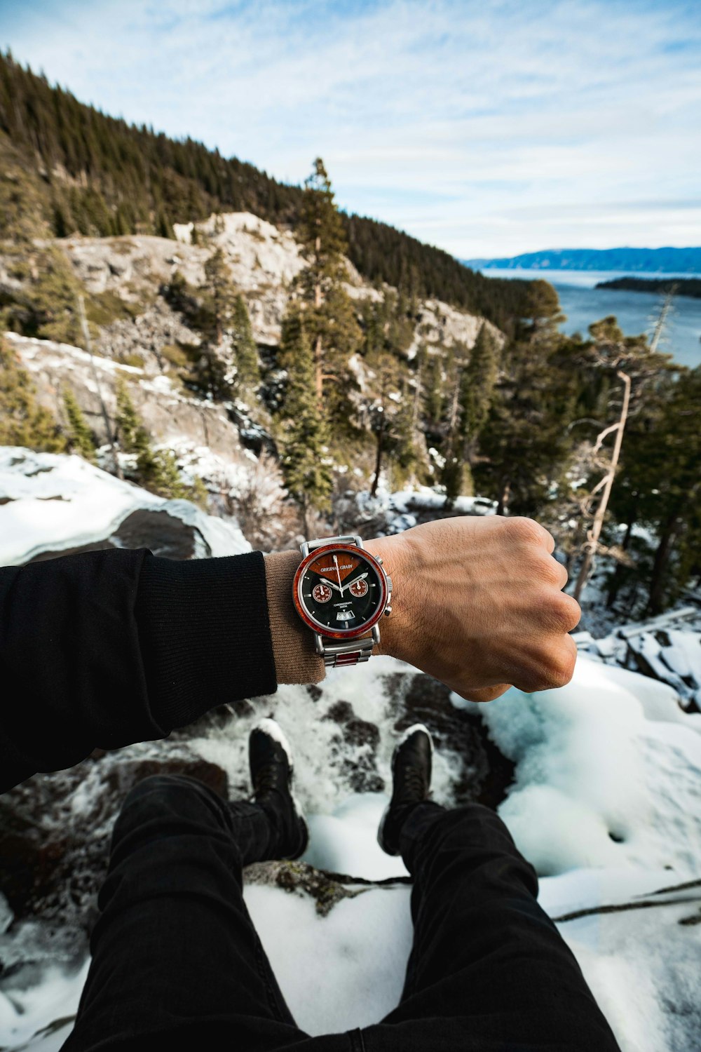 person wearing chronograph watch on top of mountain