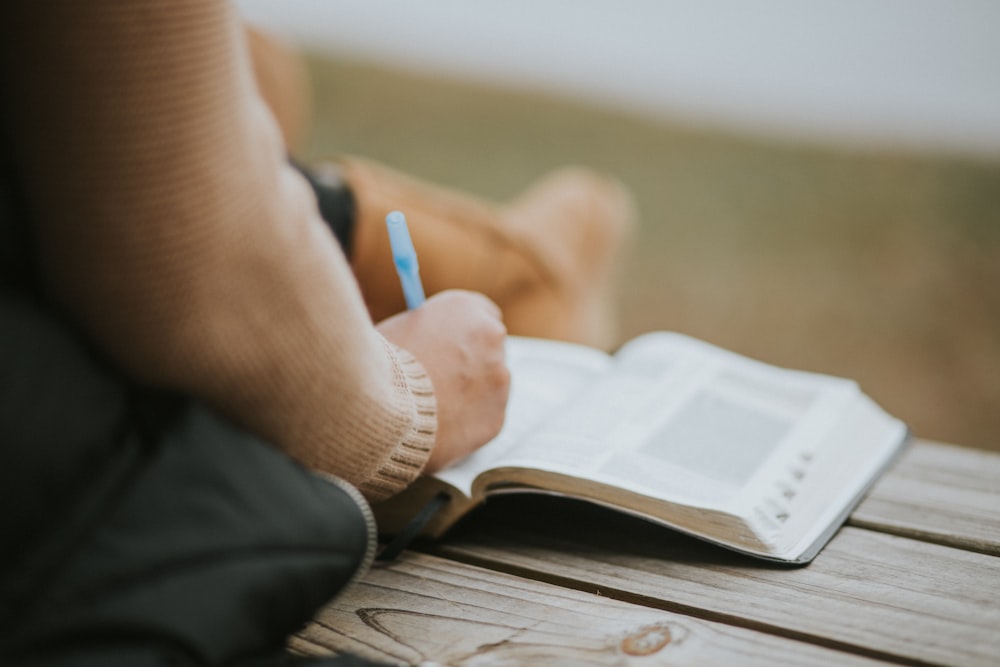 close-up photography of person writing on book page