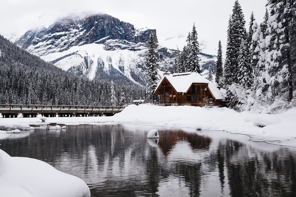 Photo d’un plan d’eau près d’une maison brune recouverte de neige