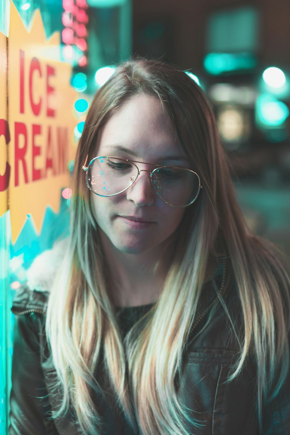 woman wearing black leather zip-up jacket standing beside ice cream sticker at night