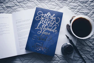 closed All the Letters I Should Have Sent novel book beside filled white cup
