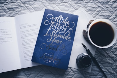 closed All the Letters I Should Have Sent novel book beside filled white cup