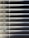 Horizontal blinds partially closed with minimal light seeping through, creating a pattern of alternating light and shadow. A pull cord hangs on the left side of the blinds.