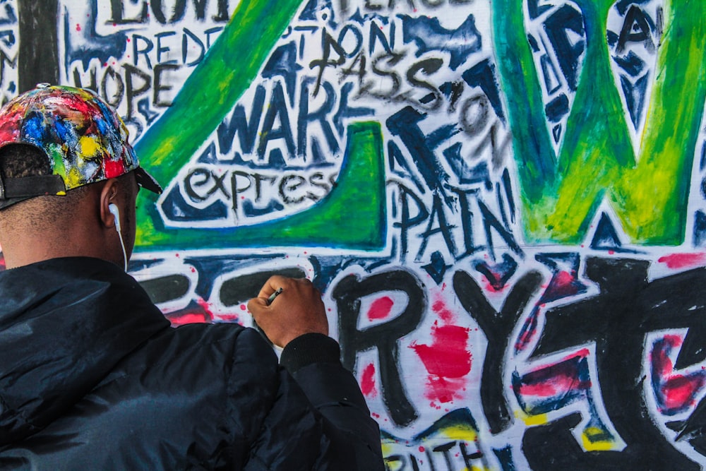 hombre con chaqueta negra pintando graffiti