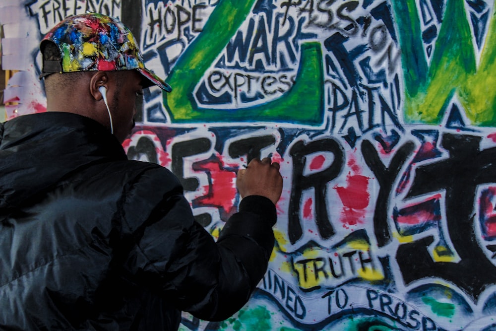 man spraying graffiti on wall during daytime