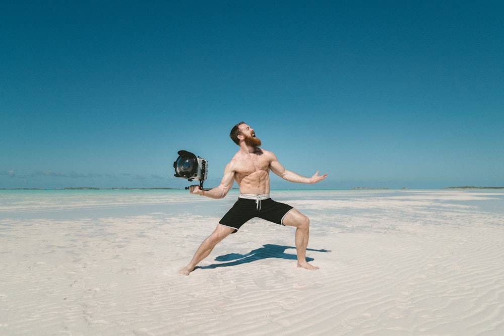 man holding camera on seashore