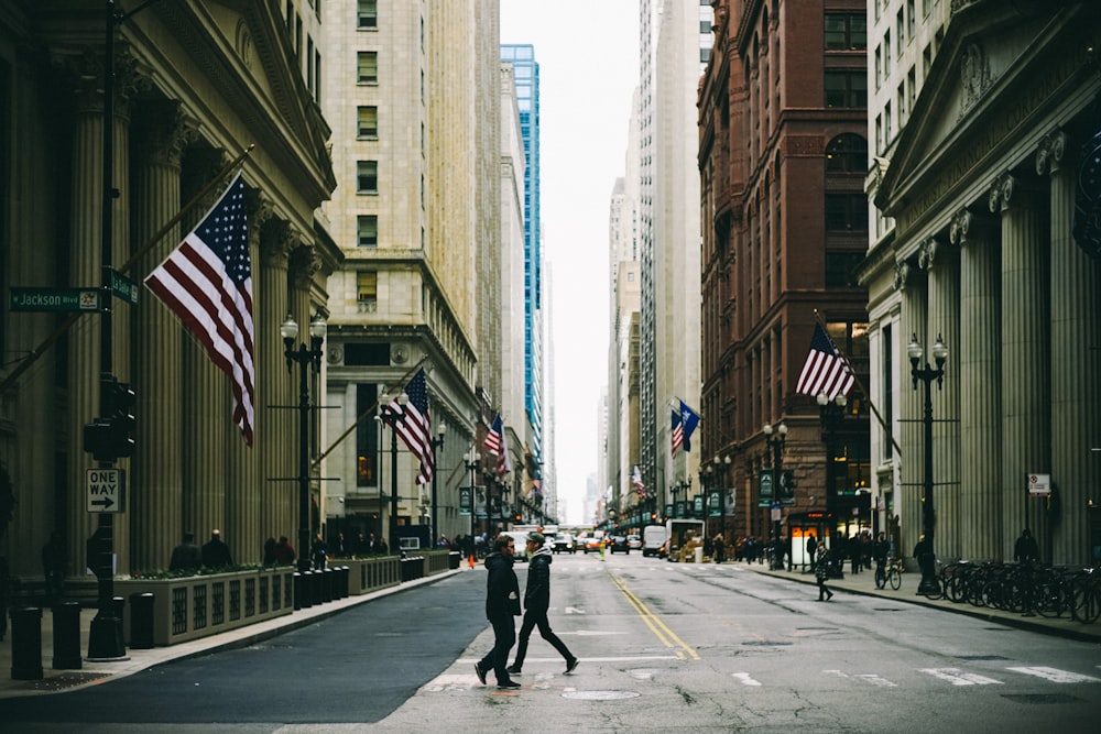 people walking on street near flag of U.S. America