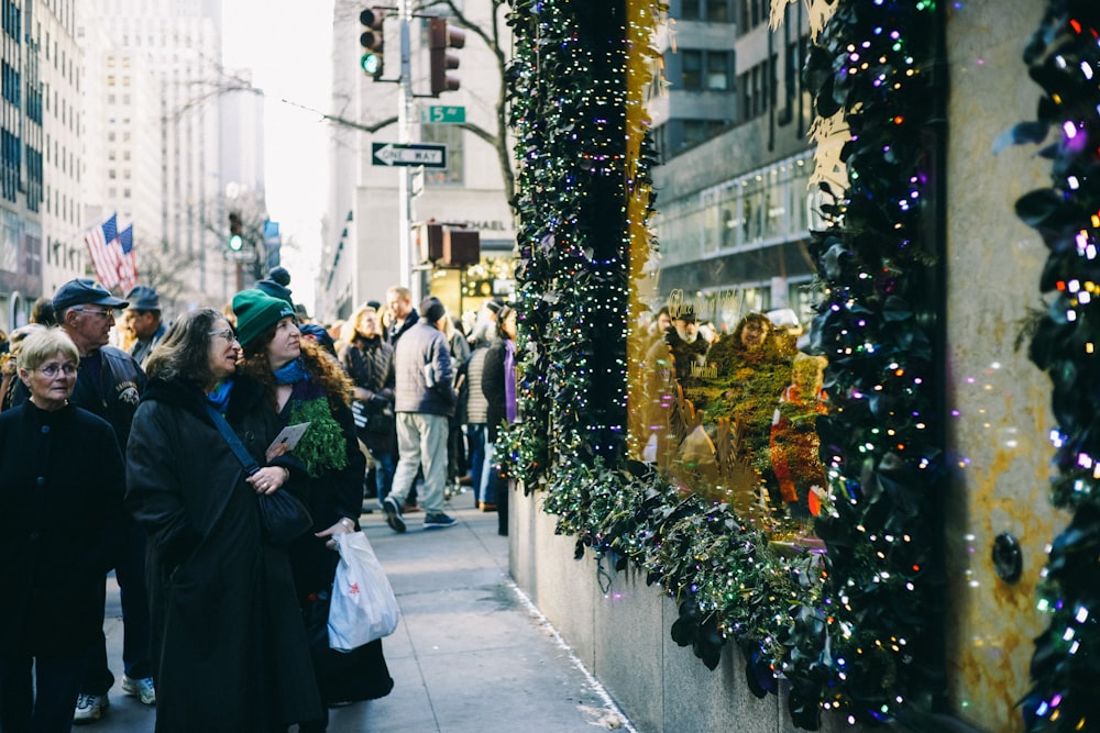 people in sidewalk staring at string lights