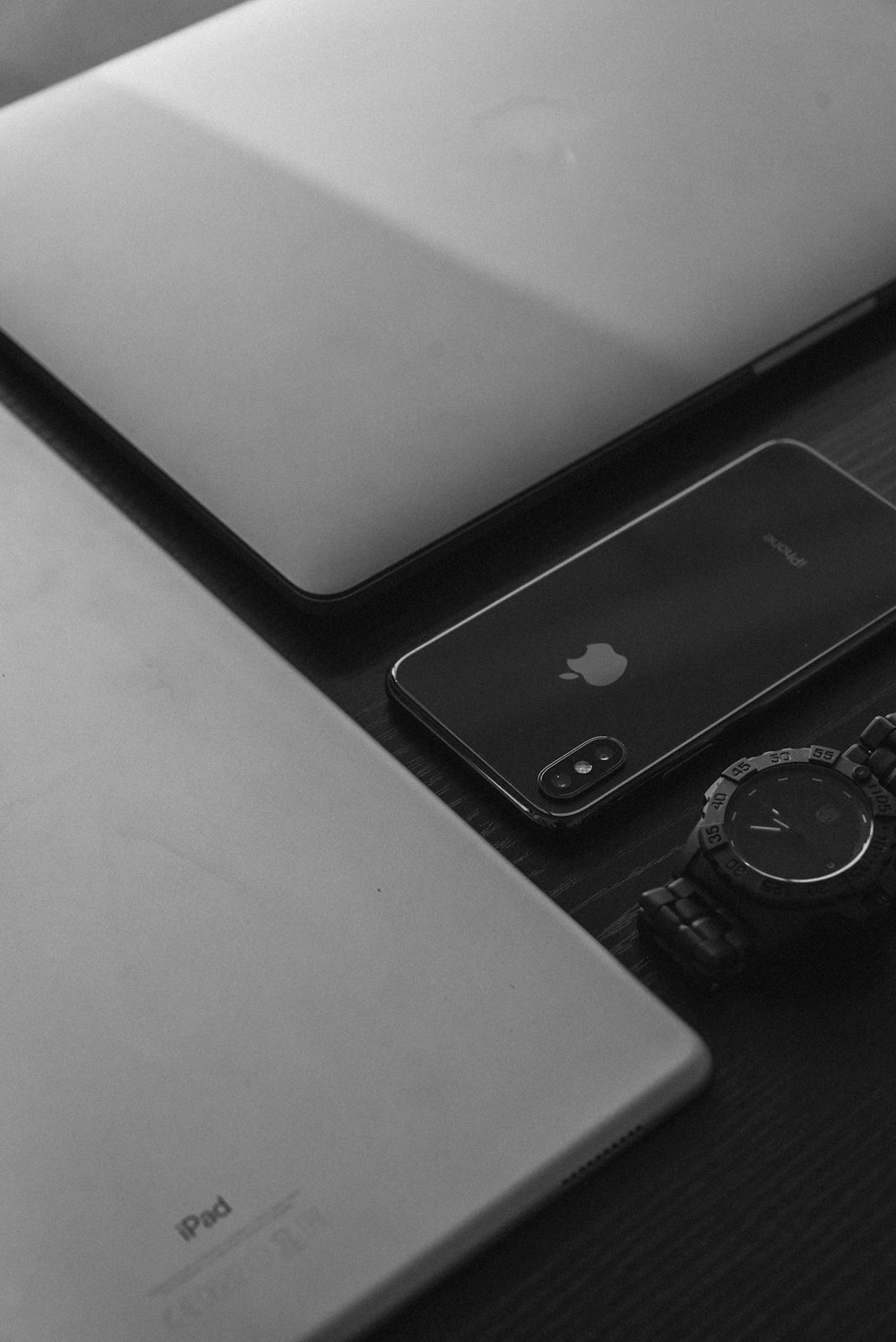 シルバーのApple MacBook、シルバーのiPad、スペースグレイのiPhone X、ブラックのアナログウォッチ