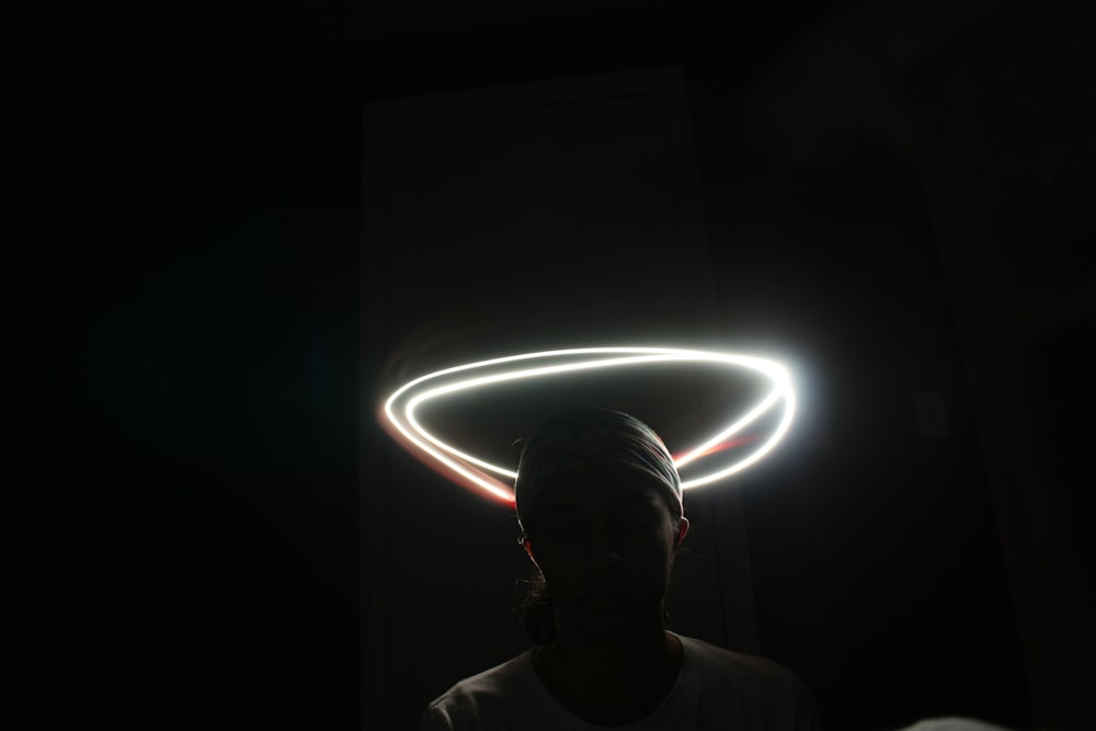 暗い部屋に頭に光の輪を巻いて立っている男