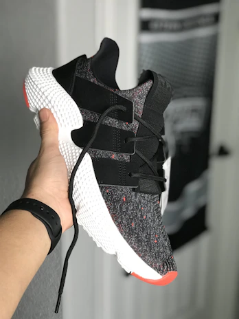 Close-up of hands holding a pair of stylish sneakers with bold patterns.