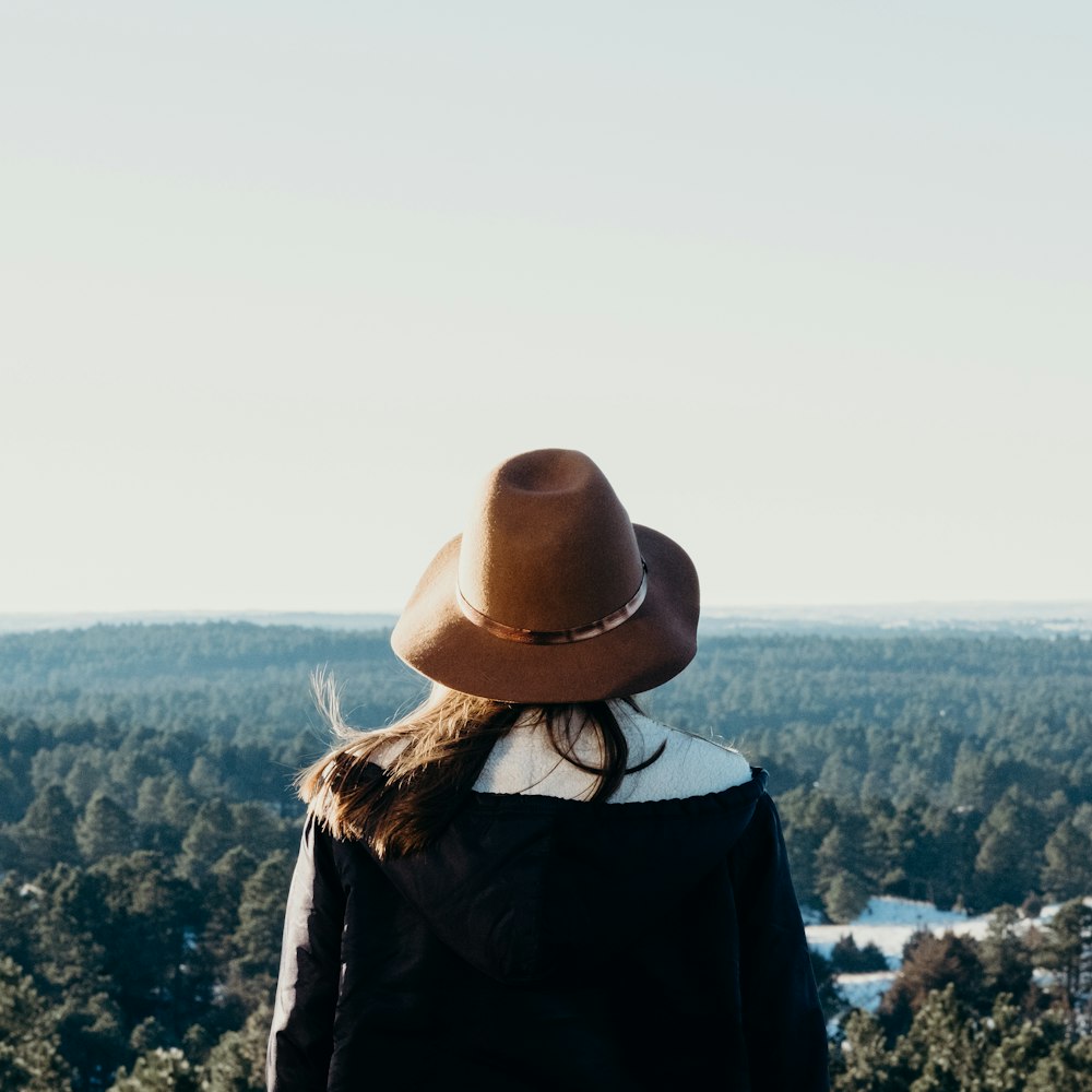 緑の木々のある山の上に立つ女性