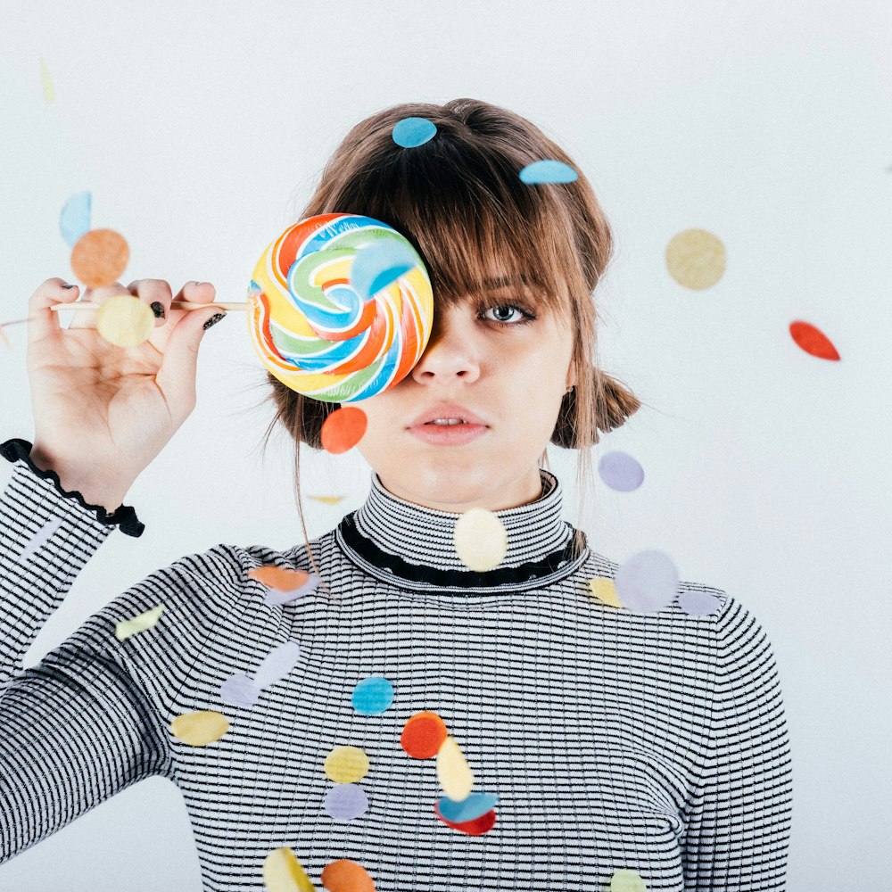 woman covering her right eye with lollipop