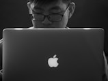 Technician running diagnostics on a MacBook with a focused expression.