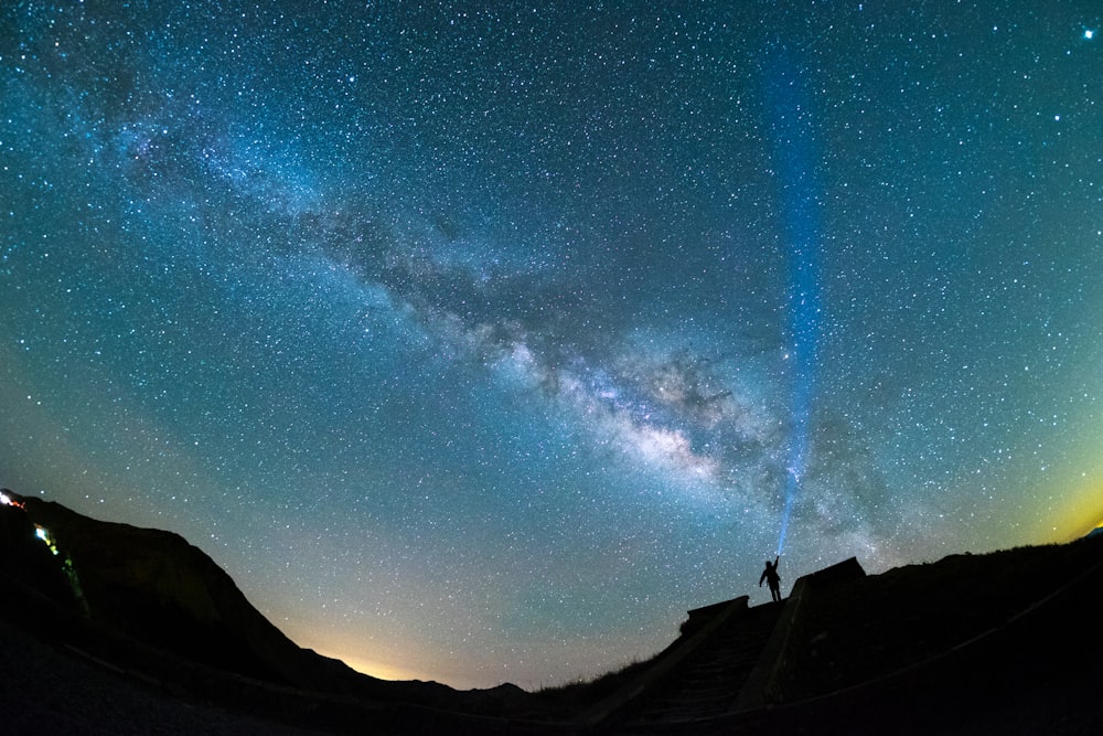 Silhouette eines Mannes, der die Hände über den Sternenhimmel hebt